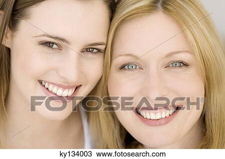 Stock Image - Portrait of two women smiling for the camera, indoors. Fotosearch