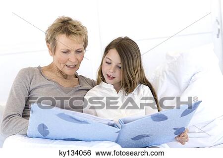 Senior woman and little girl in bed, looking at photograph album View Large Photo Image Stock Photograph - Senior woman and little girl in bed, looking at photograph album. Fotosearch