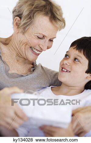 Stock Photo - Senior woman giving present to little boy, indoors. Fotosearch