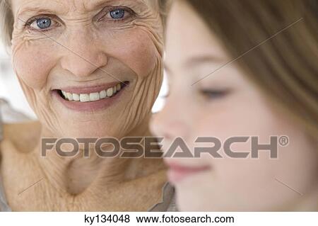 Stock Photo - Senior woman smiling for the camera, little girl in foreground, indoors. Fotosearch