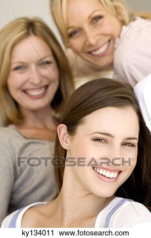 Stock Image - Three women smiling for the camera, indoors. Fotosearch