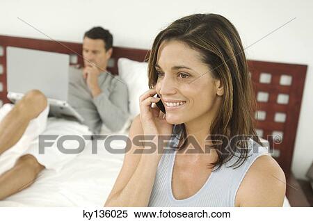 Couple in bedroom, woman phoning, indoors View Large Photo Image Stock Photography - Couple in bedroom, woman phoning, indoors. Fotosearch