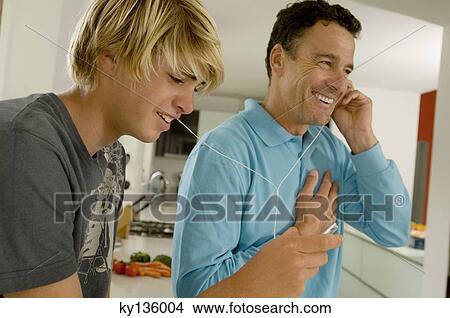 Father and son listening to music with MP3 player, indoors View Large Photo Image Picture - Father and son listening to music with MP3 player, indoors. Fotosearch