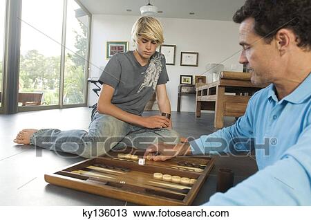 Stock Image - Father and son playing backgammon, indoors. Fotosearch