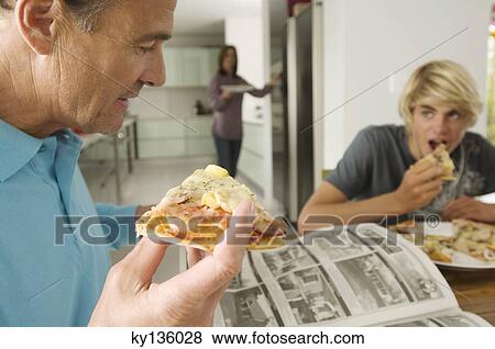 Father and teenager eating pizza, mother in background, indoors View Large Photo Image Stock Photo - Father and teenager eating pizza, mother in background, indoors. Fotosearch