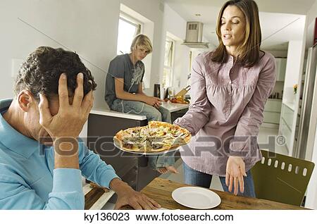 Parents and teenager in living room, woman holding a pizza, indoors View Large Photo Image Stock Image - Parents and teenager in living room, woman holding a pizza, indoors. Fotosearch