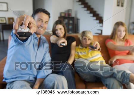 Stock Photography - Parents and two teens holding eachothers a remote control, indoors. Fotosearch