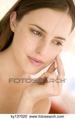 Portrait of a woman using a cleansing cotton on her cheek, indoors View Large Photo Image Stock Image - Portrait of a woman using a cleansing cotton on her cheek, indoors. Fotosearch