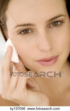 Portrait of a woman using a cleansing cotton on her cheek, indoors View Large Photo Image Stock Photograph - Portrait of a woman using a cleansing cotton on her cheek, indoors. Fotosearch