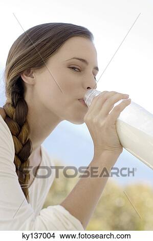 Portrait of a young woman drinking milk from the bottle, outdoors View Large Photo Image Picture - Portrait of a young woman drinking milk from the bottle, outdoors. Fotosearch
