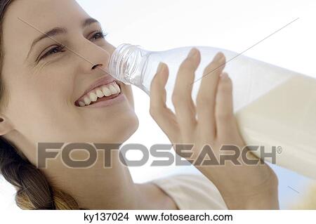 Portrait of a young woman drinking milk from the bottle, outdoors View Large Photo Image Picture - Portrait of a young woman drinking milk from the bottle, outdoors. Fotosearch
