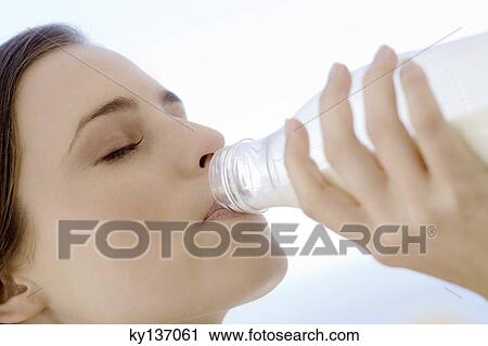 Portrait of a young woman drinking milk from the bottle, outdoors View Large Photo Image Stock Image - Portrait of a young woman drinking milk from the bottle, outdoors. Fotosearch