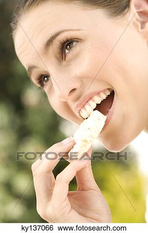 Portrait of a young woman eating a biscuit, outdoors View Large Photo Image Stock Photograph - Portrait of a young woman eating a biscuit, outdoors. Fotosearch