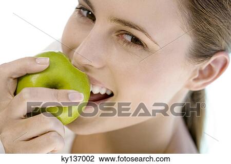 Portrait of a young woman eating an apple, indoors View Large Photo Image Stock Image - Portrait of a young woman eating an apple, indoors. Fotosearch