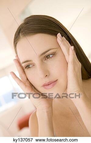 Portrait of a young woman, hands on her cheeks, indoors View Large Photo Image Stock Photo - Portrait of a young woman, hands on her cheeks, indoors. Fotosearch