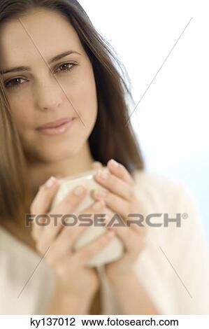 Portrait of a young woman holding a cup, indoors View Large Photo Image Stock Image - Portrait of a young woman holding a cup, indoors. Fotosearch