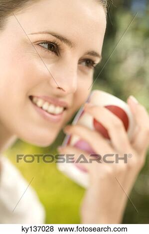 Portrait of a young woman holding a cup, indoors View Large Photo Image Stock Photo - Portrait of a young woman holding a cup, indoors. Fotosearch