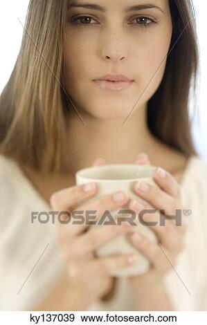 Portrait of a young woman holding a cup, indoors View Large Photo Image Stock Photo - Portrait of a young woman holding a cup, indoors. Fotosearch