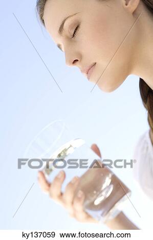 Stock Photo - Portrait of a young woman holding a water glass, outdoors. Fotosearch
