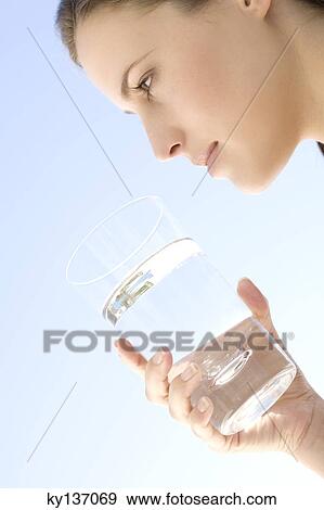 Portrait of a young woman holding a water glass, outdoors View Large Photo Image Stock Photo - Portrait of a young woman holding a water glass, outdoors. Fotosearch