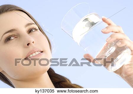 Portrait of a young woman holding a water glass, outdoors View Large Photo Image Stock Photography - Portrait of a young woman holding a water glass, outdoors. Fotosearch