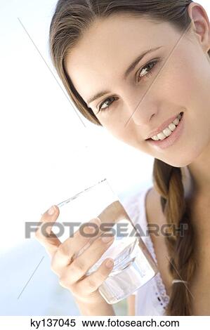 Portrait of a young woman holding a water glass, outdoors View Large Photo Image Stock Photography - Portrait of a young woman holding a water glass, outdoors. Fotosearch