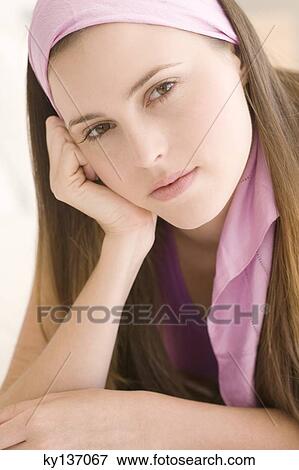 Stock Photo - Portrait of a young woman looking at the camera, indoors. Fotosearch