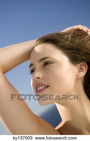 Portrait of a young woman looking away, hand in her hair, outdoors View Large Photo Image Stock Image - Portrait of a young woman looking away, hand in her hair, outdoors. Fotosearch