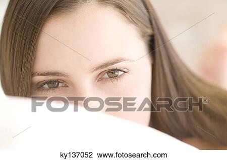 Stock Image - Portrait of a young woman lying, indoors. Fotosearch