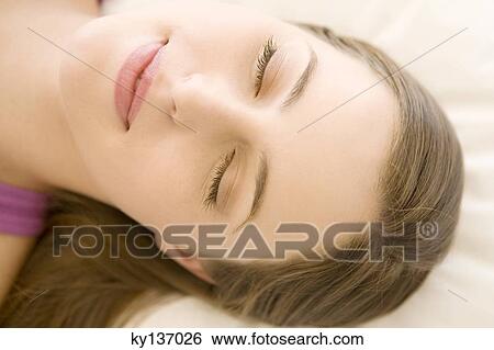 Stock Photograph - Portrait of a young woman lying, sleeping, indoors. Fotosearch