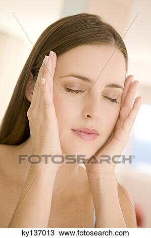 Portrait of a young woman shut eyes, hands on her cheeks, indoors View Large Photo Image Stock Image - Portrait of a young woman shut eyes, hands on her cheeks, indoors. Fotosearch