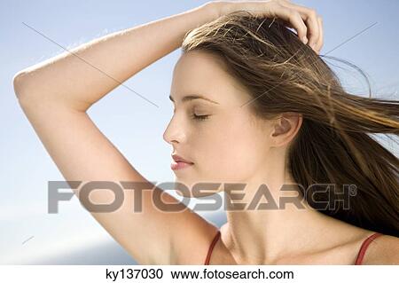 Portrait of a young woman, shut eyes, hand in her hair, outdoors View Large Photo Image Stock Image - Portrait of a young woman, shut eyes, hand in her hair, outdoors. Fotosearch