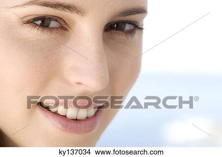 Portrait of a young woman smiling, looking at the camera, indoors View Large Photo Image Picture - Portrait of a young woman smiling, looking at the camera, indoors. Fotosearch