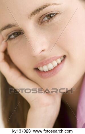 Portrait of a young woman smiling, looking at the camera, indoors View Large Photo Image Stock Image - Portrait of a young woman smiling, looking at the camera, indoors. Fotosearch