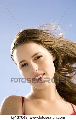 Portrait of a young woman smiling, posing for the camera, outdoors View Large Photo Image Stock Photo - Portrait of a young woman smiling, posing for the camera, outdoors. Fotosearch