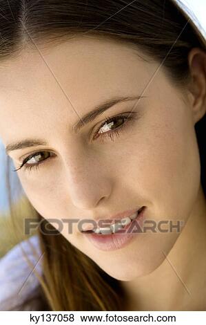 Stock Photo - Portrait of a young woman smiling, looking at the camera, indoors. Fotosearch