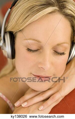 Stock Photograph - Young woman listening to music with headphones. Fotosearch