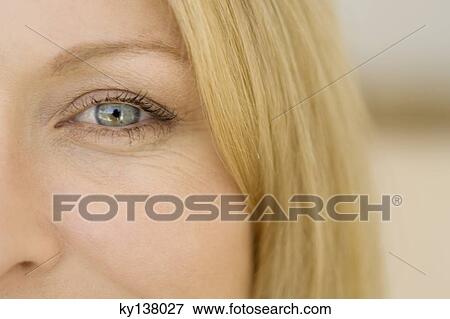 Stock Photo - Young woman looking at camera, close-up of eye. Fotosearch
