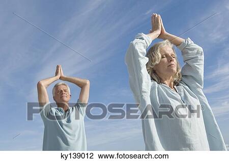 Stock Image - Couple in yoga attitude on the beach, outdoors. Fotosearch