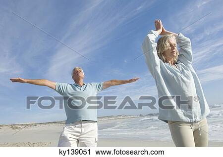 Couple in yoga attitude on the beach, outdoors View Large Photo Image Stock Image - Couple in yoga attitude on the beach, outdoors. Fotosearch