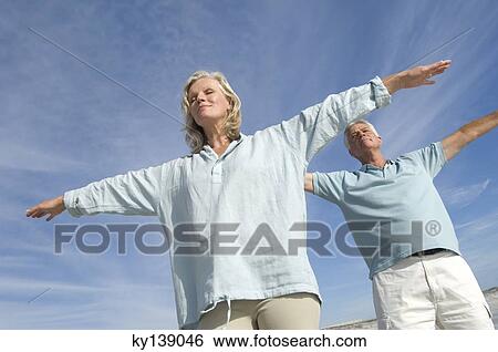 Stock Photograph - Couple in yoga attitude on the beach, outdoors. Fotosearch