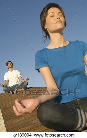 Picture - Young couple in yoga attitude, outdoors. Fotosearch