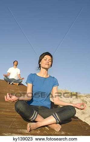 Stock Image - Young couple in yoga attitude, outdoors. Fotosearch