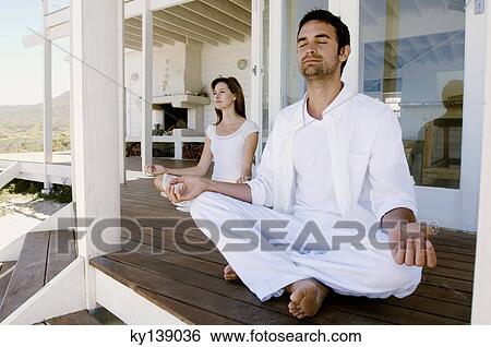 Stock Photograph - Young couple in yoga attitude, outdoors. Fotosearch