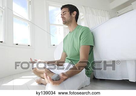 Young man in yoga attitude, indoors View Large Photo Image Picture - Young man in yoga attitude, indoors. Fotosearch