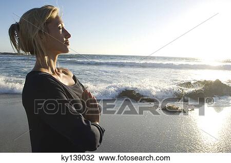 Stock Image - Young woman in yoga attitude on the beach, outdoors. Fotosearch