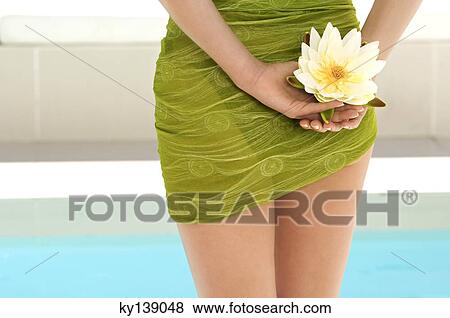 Young woman near a pool, holding a water lily, outdoors View Large Photo Image Stock Photo - Young woman near a pool, holding a water lily, outdoors. Fotosearch