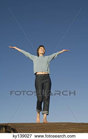 Stock Photo - Young woman on a pontoon, outdoors. Fotosearch