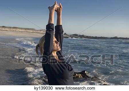 Young woman on the beach, stretching, outdoors View Large Photo Image Stock Image - Young woman on the beach, stretching, outdoors. Fotosearch