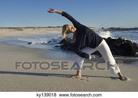 Young woman stretching on the beach, outdoors View Large Photo Image Stock Photo - Young woman stretching on the beach, outdoors. Fotosearch